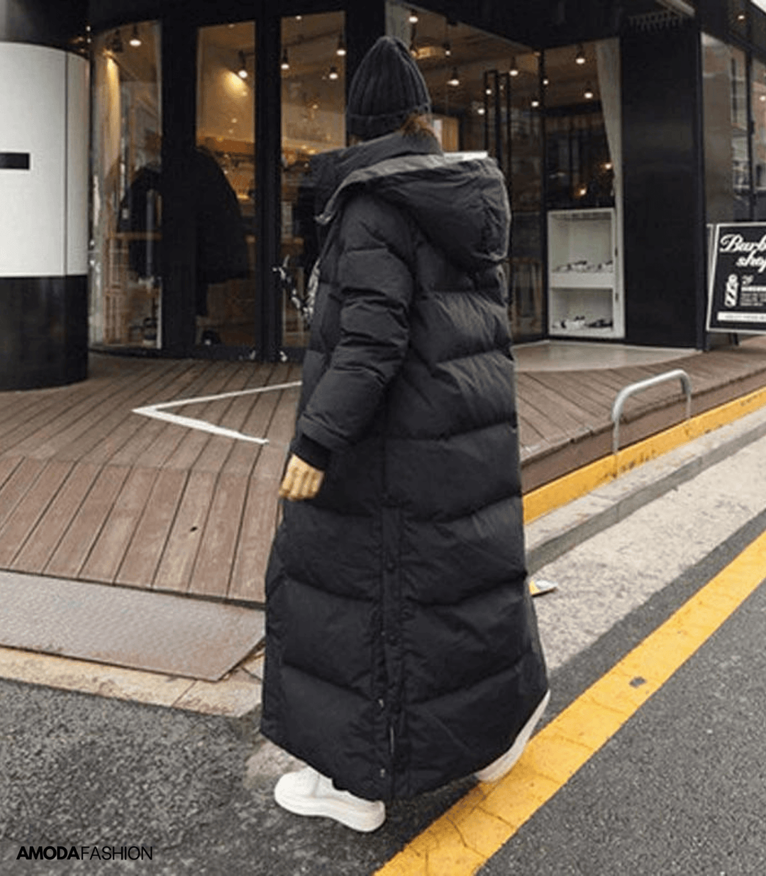 Back view of woman walking in a black oversized long winter parka