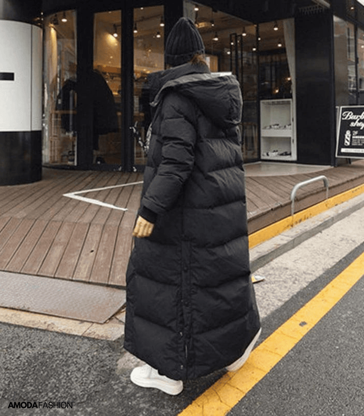 Back view of woman walking in a black oversized long winter parka