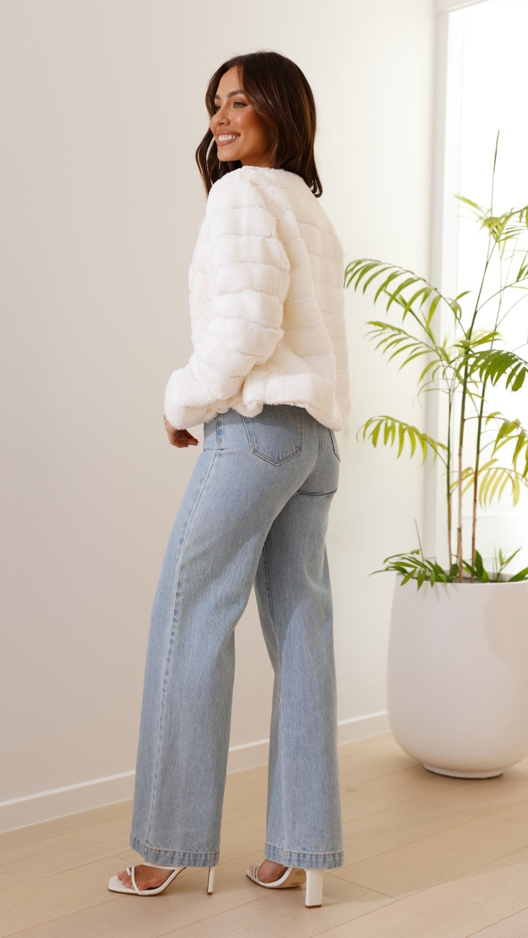 Side profile of woman wearing white cropped jacket and jeans