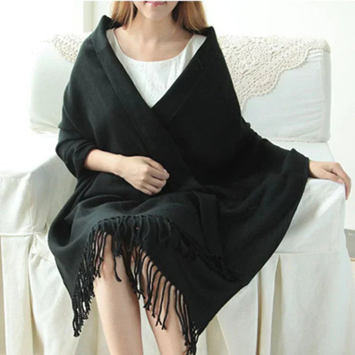 Woman wearing black winter scarf seated on white couch