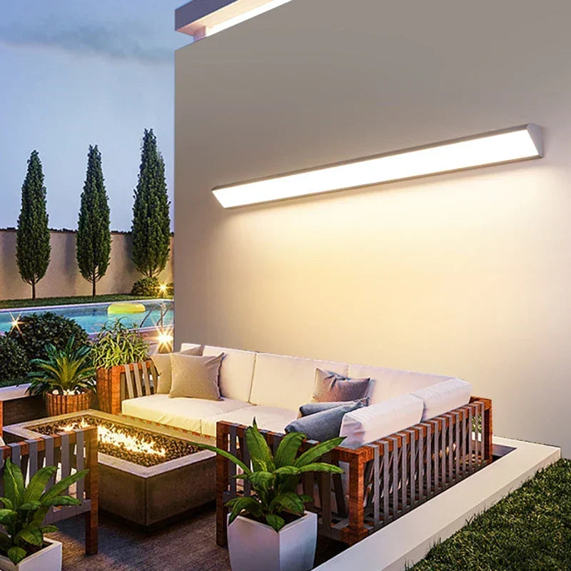 Modern LED outdoor wall light illuminating a luxury patio seating area at dusk