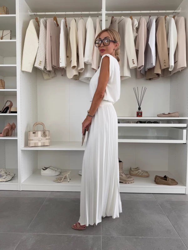 Side view of woman wearing a white sleeveless coordinated outfit with wide leg trousers