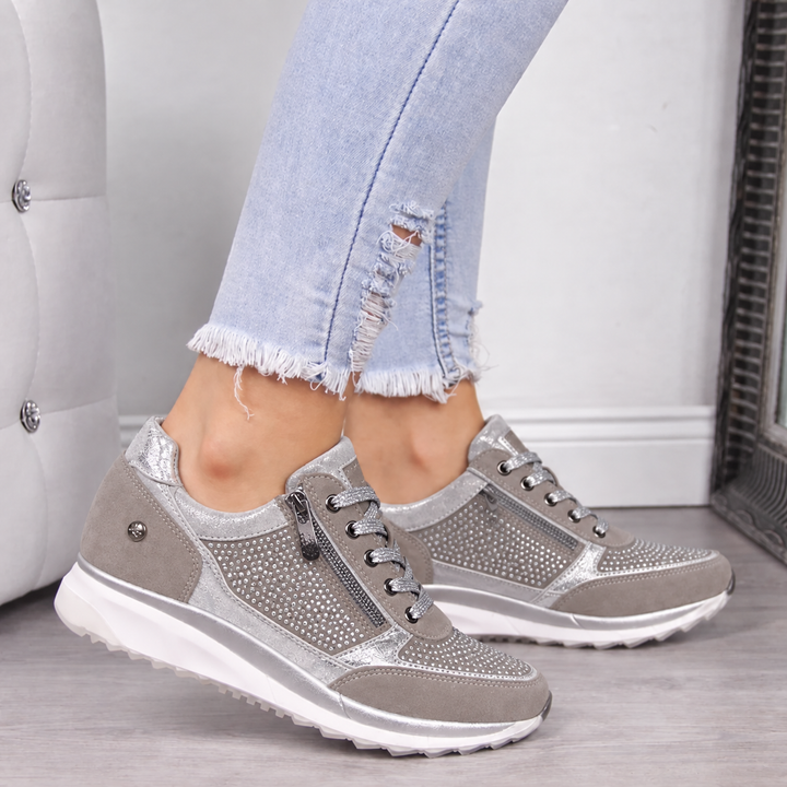 Woman wearing grey studded orthopedic sneakers with side zip and distressed jeans