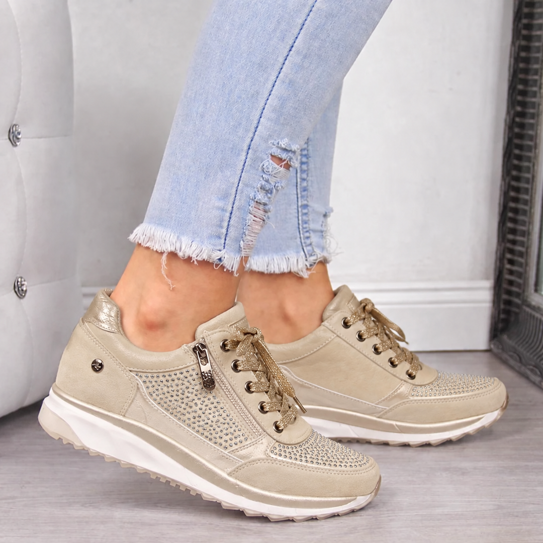 Woman wearing beige studded orthopedic sneakers with side zip and metallic accents