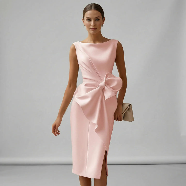 Model wearing a pink midi dress with a sculpted waist bow and holding a clutch