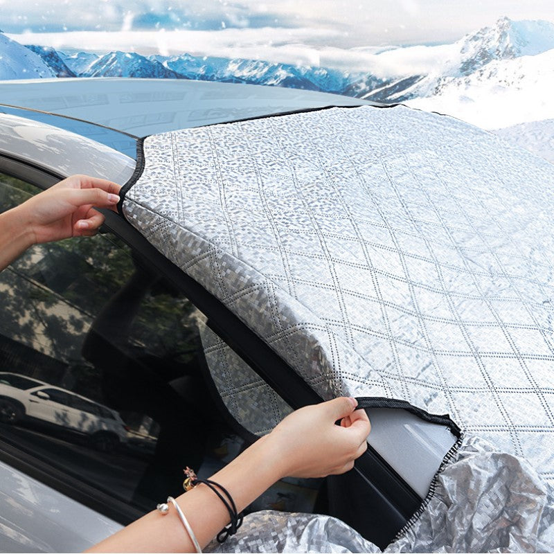 Person securing magnetic car snow cover on a vehicle windshield