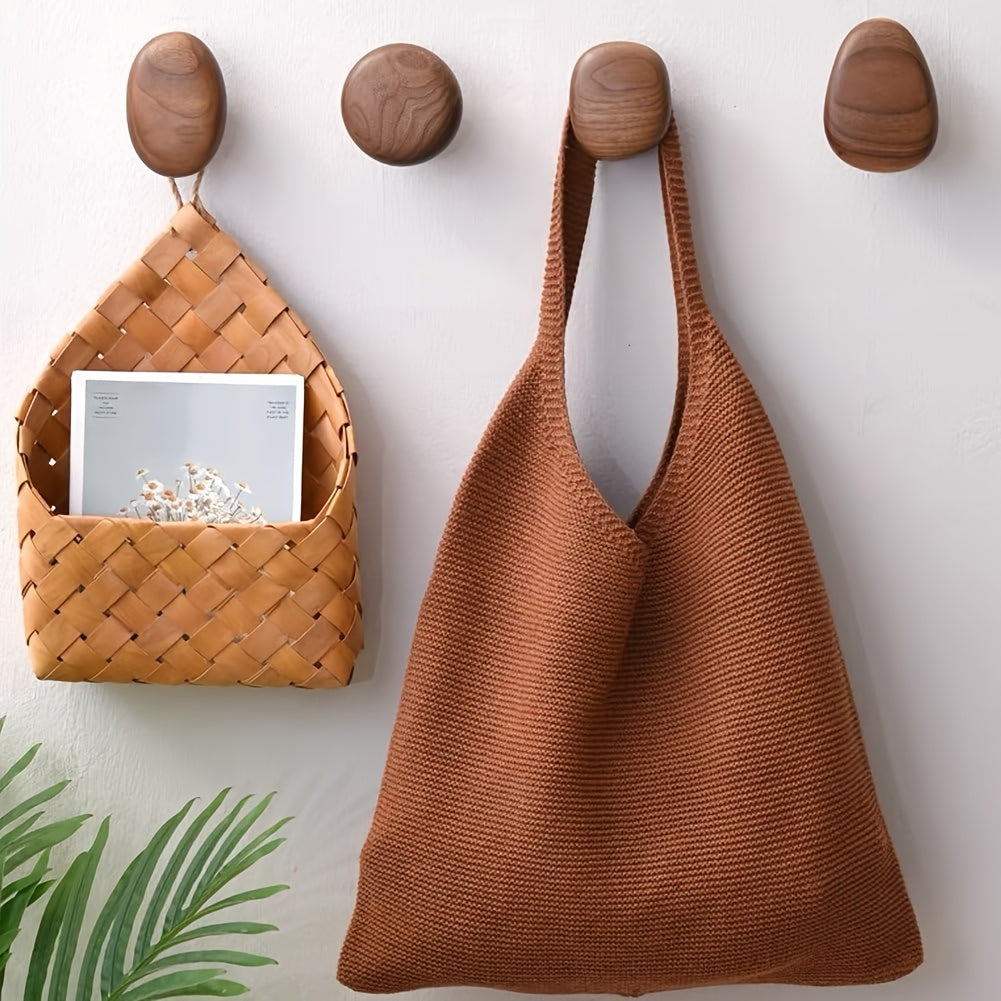Close-up view of round walnut wooden wall hooks holding a woven bag against a light wall