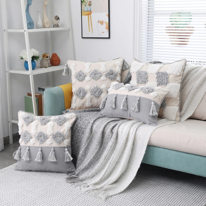 Collection of bohemian tufted cushion covers arranged on a grey sofa in a brightly lit living room