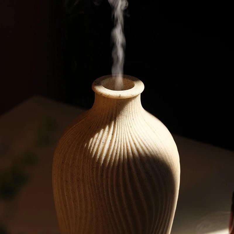 Boho decor aroma diffuser lit up with warm LED lights in a cozy living room.