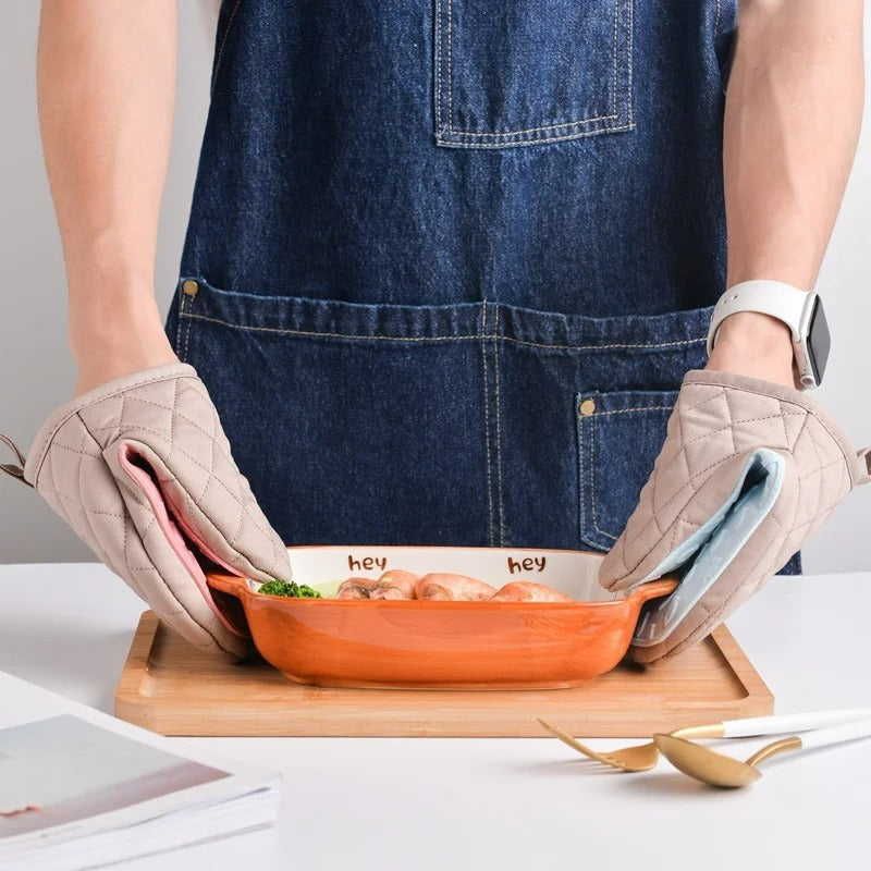 Person wearing pink and mint fish shaped silicone oven gloves holding a ceramic casserole dish