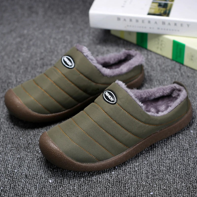 Pair of green winter lined slippers on a grey textured surface