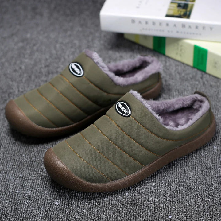 Pair of green winter lined slippers on a grey textured surface