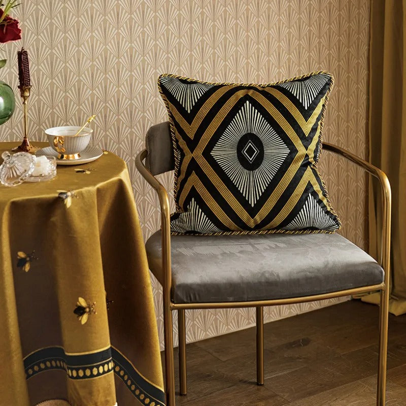 Golden bee decorative cushion cover placed on a stylish grey chair in a warmly lit room