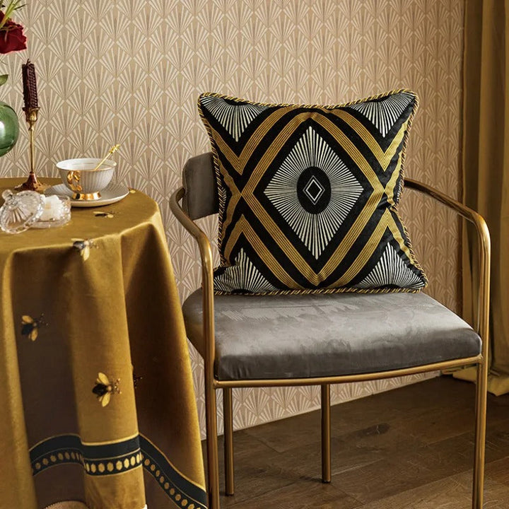 Golden bee decorative cushion cover placed on a stylish grey chair in a warmly lit room