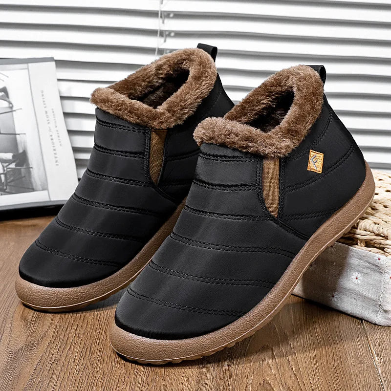 Pair of black winter slip-on shoes with plush lining and textured soles on wooden surface.