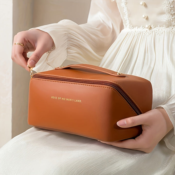 Brown travel makeup organizer bag held by a person wearing white dress