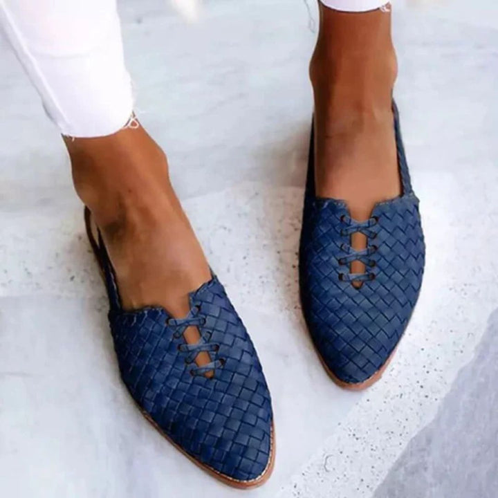 Blue woven slip-on sandals paired with white trousers
