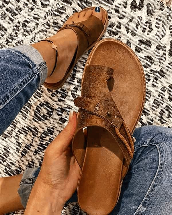 Brown women's orthopedic toe loop sandal held in hand showcasing detail