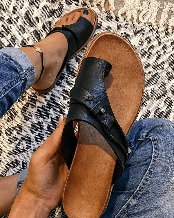 Black women's orthopedic toe loop sandal worn on foot with jeans