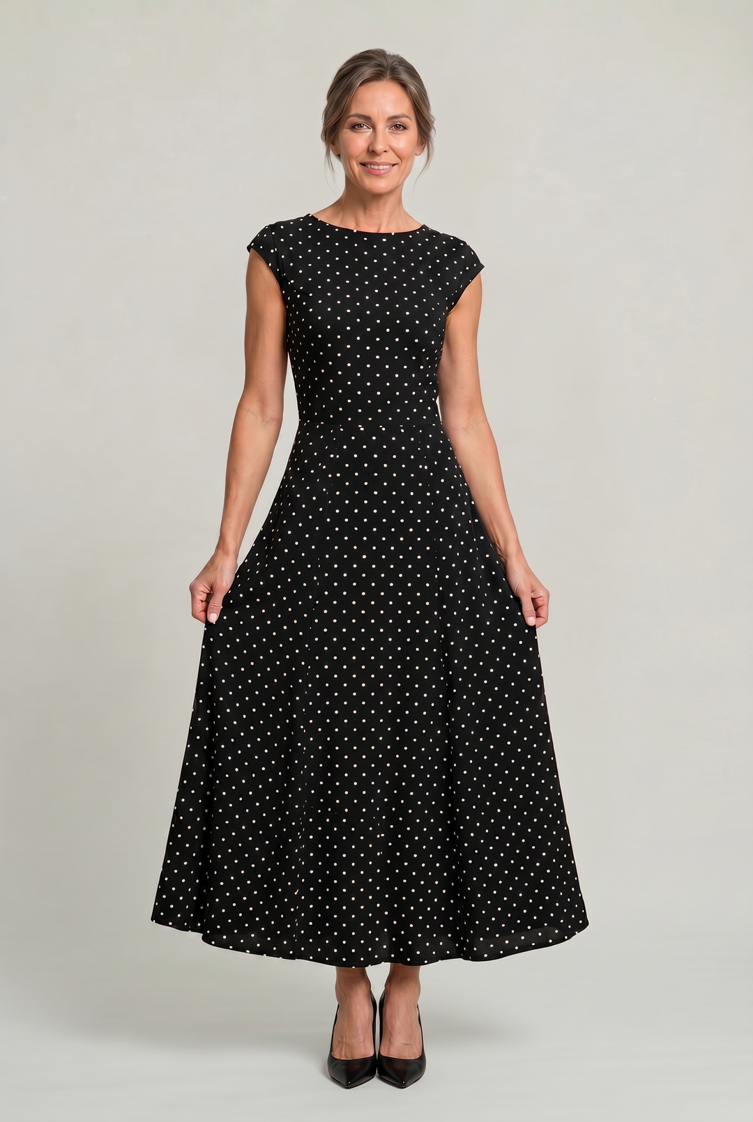 Woman wearing a black polka dot maxi party dress with cap sleeves, front view