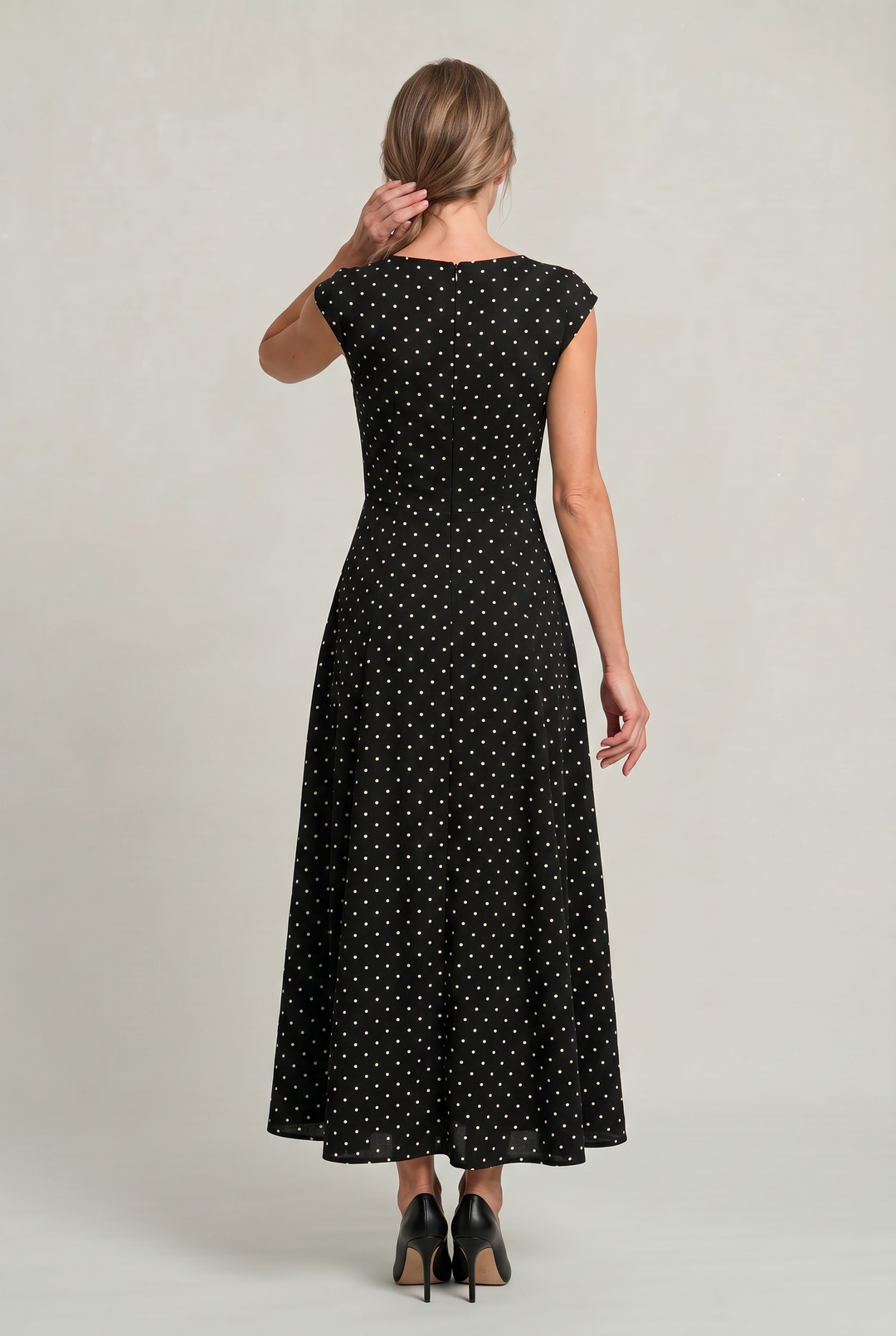 Back view of a woman wearing a black polka dot maxi dress with back zip closure