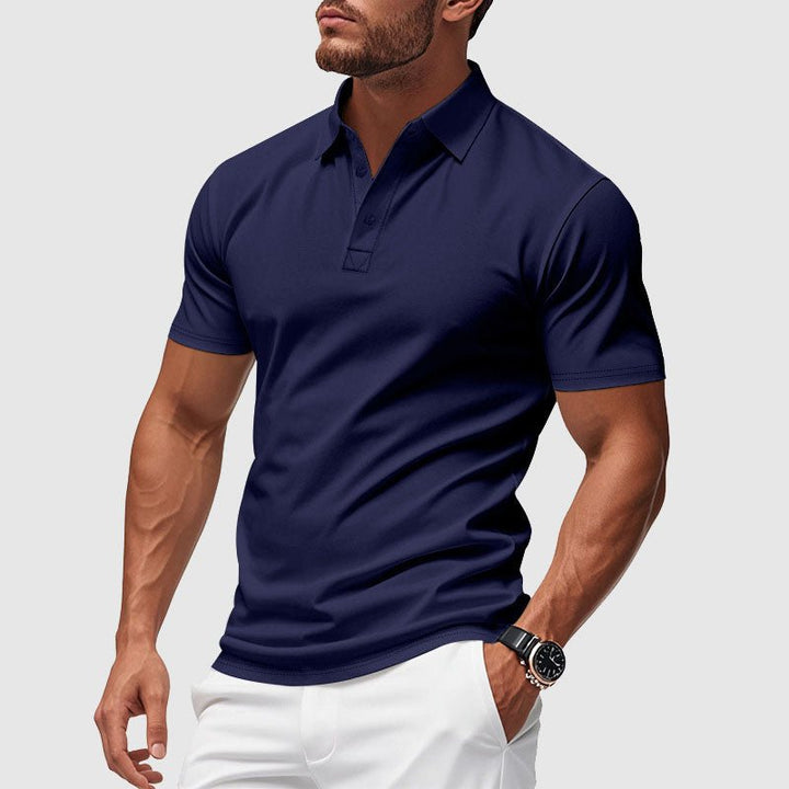A man wearing a blue short-sleeve performance polo shirt with white trousers.