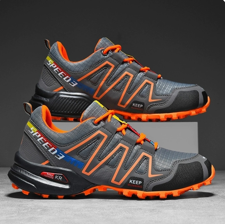 Men's gray and orange hiking shoes displayed on a studio backdrop