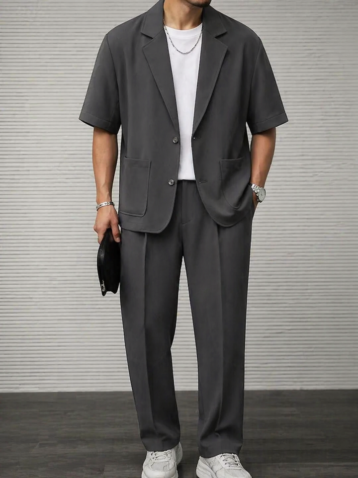 Man wearing grey short-sleeve blazer and tailored trousers set from the front