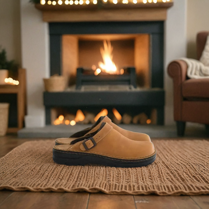 Men's orthopedic clogs resting on a knitted mat in front of a cozy indoor fireplace