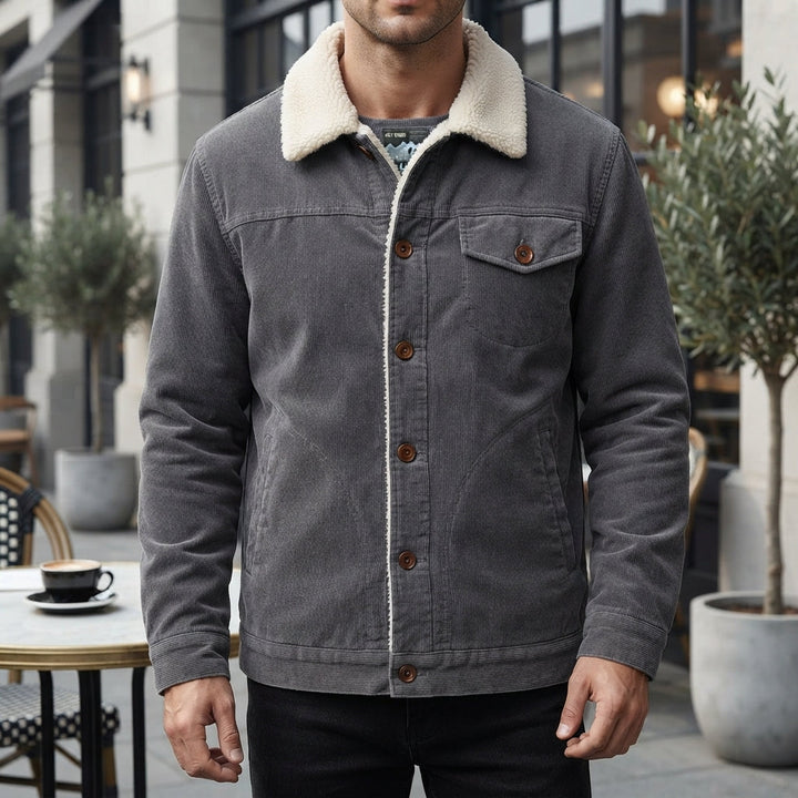 Man wearing a dark grey textured jacket standing in front of a building