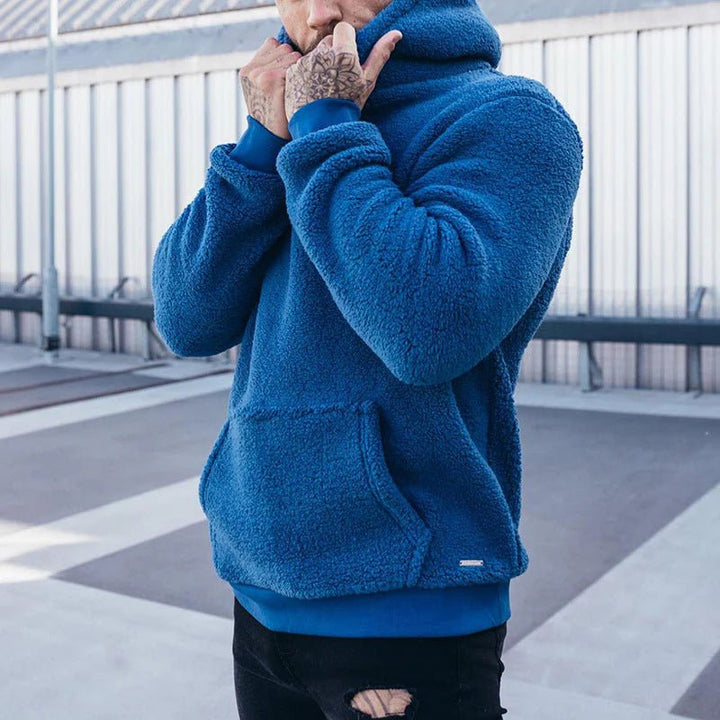 Man showcasing a blue cozy pullover hoodie with front pocket