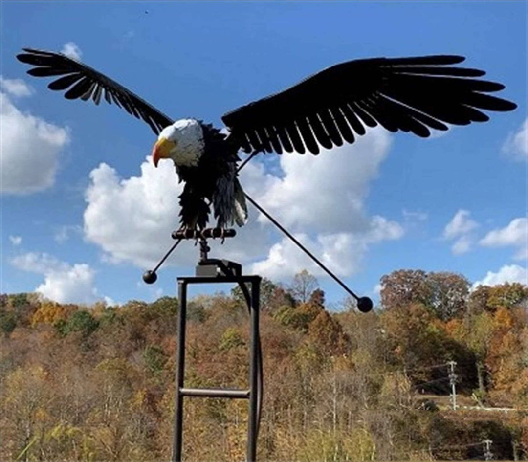 Flying eagle metal wind spinner sculpture installed outdoors in a garden