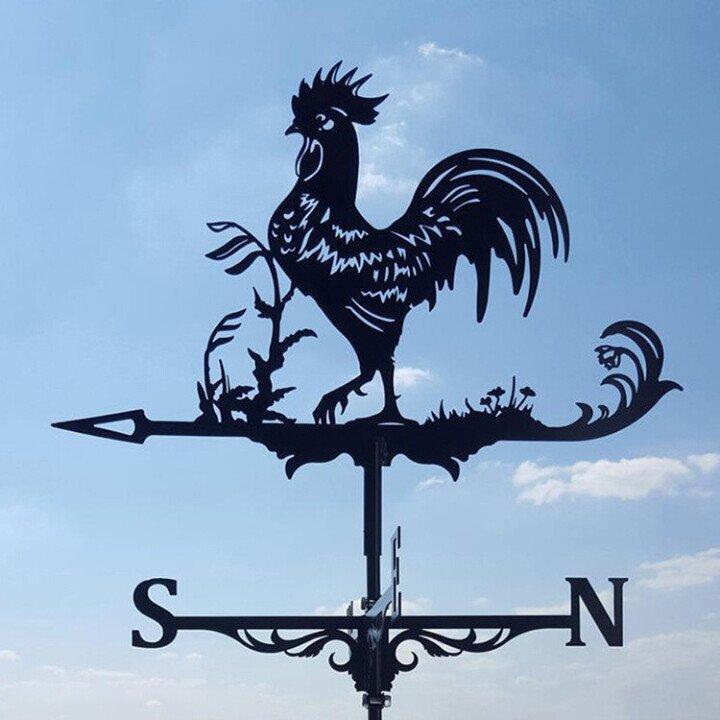 Metal weather vane featuring a rooster design mounted against a blue sky