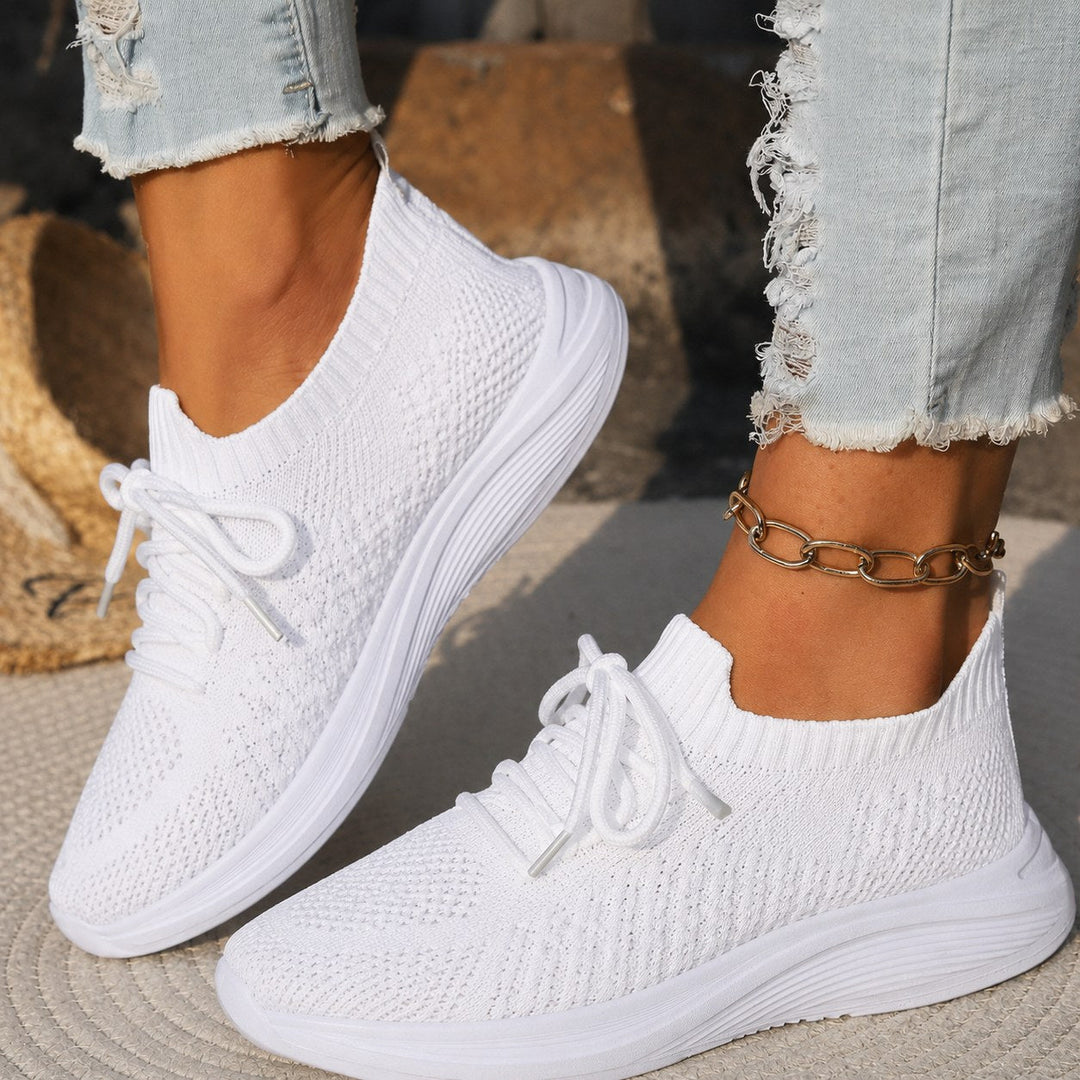 Close-up of white women's orthopedic trainer worn with distressed jeans and a gold anklet
