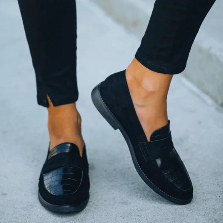 Side angle view of black Mila loafers styled with black trousers