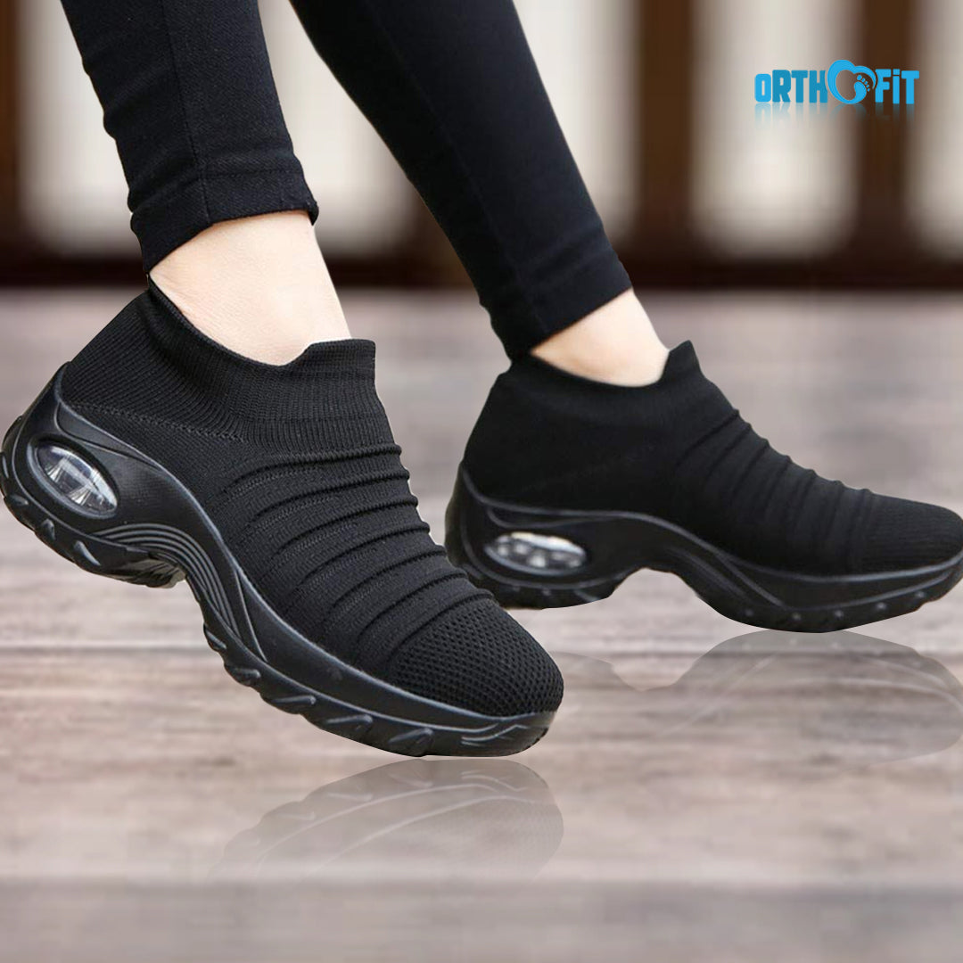 Person wearing black slip-on orthopedic walking sneakers outdoors