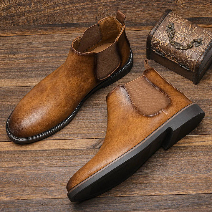 Milo men's brown Chelsea boots viewed from above on a wooden surface next to a decorative box