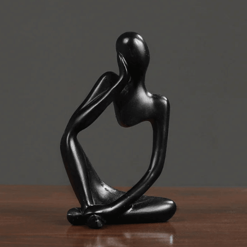 Black minimalist abstract thinker figurine displayed on wooden surface