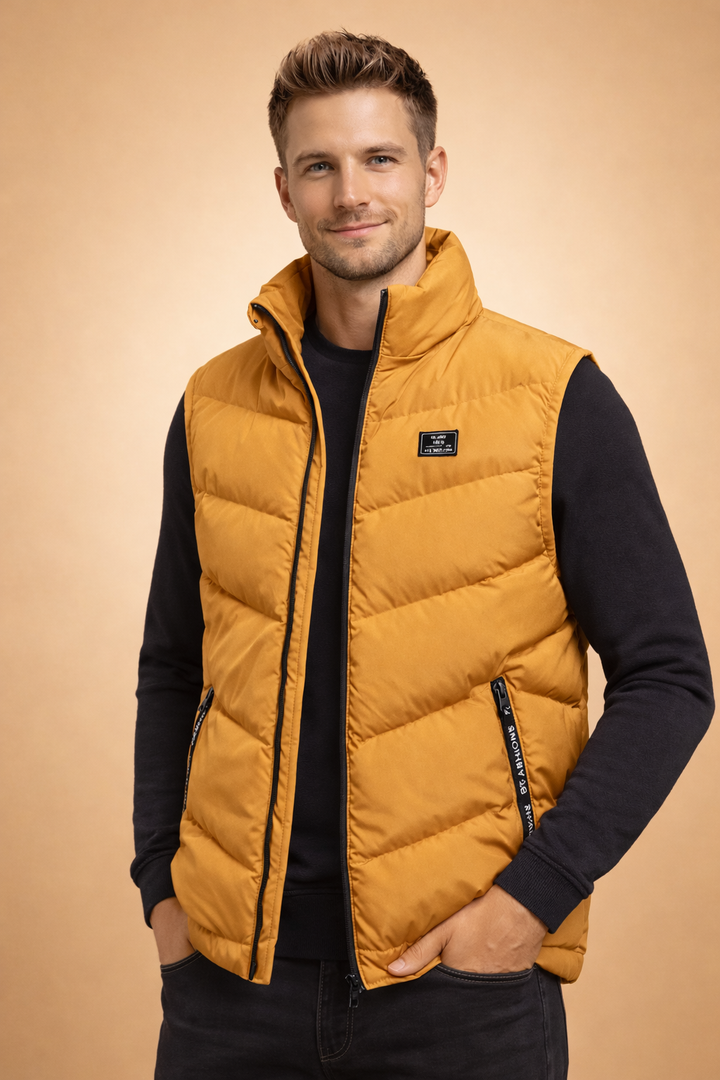 Man wearing a yellow quilted puffer vest over a black sweater