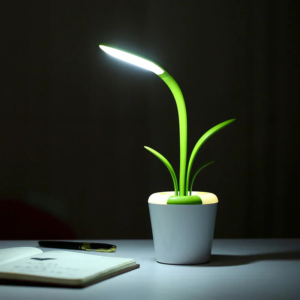 Green modern LED desk lamp in a plant pot design glowing on a dark desk