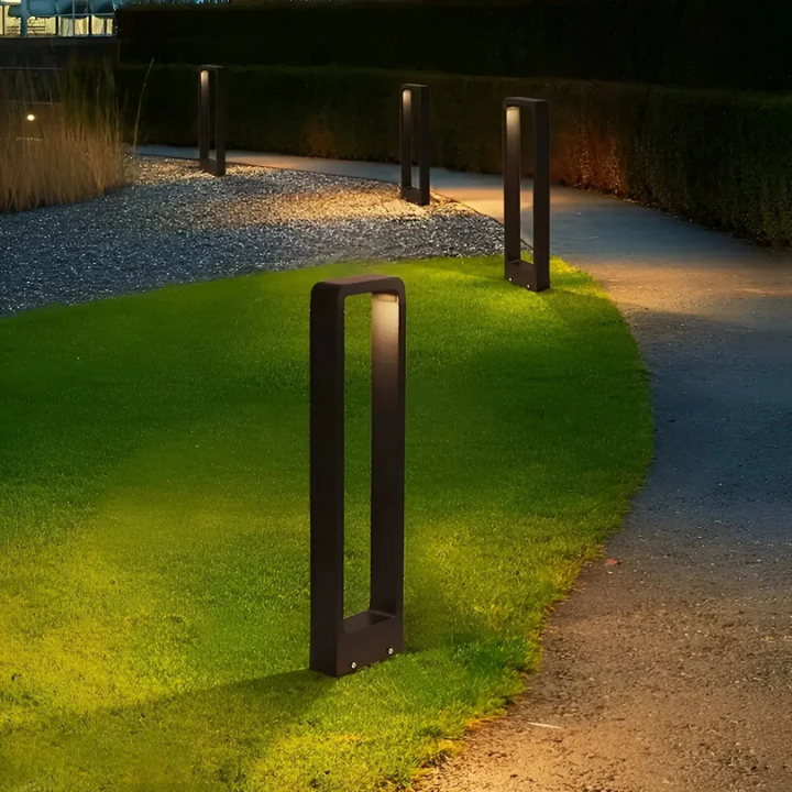 Row of modern LED garden light columns illuminating a curved pathway at dusk