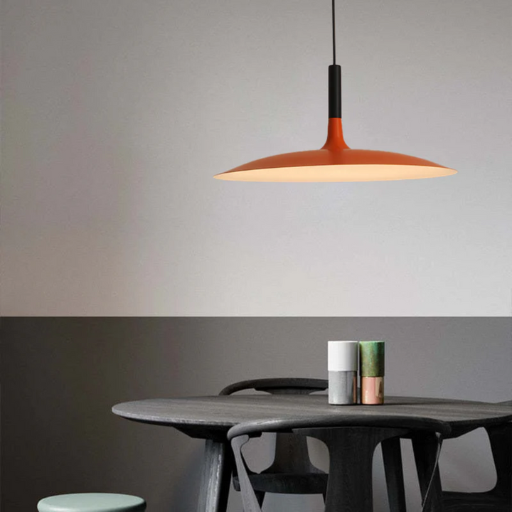 Modern orange LED pendant light hanging over a dining table