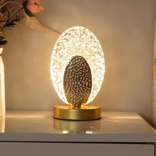 Modern peacock table lamp glowing softly on a white nightstand