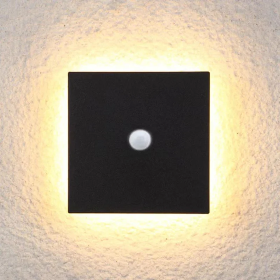 Square black modern LED wall lamp with motion sensor mounted on an exterior textured wall