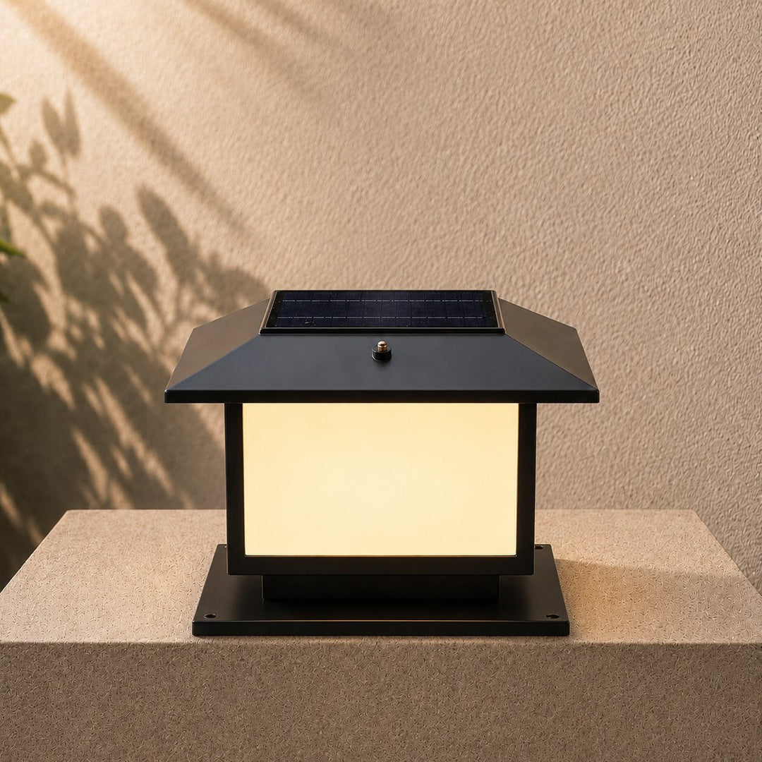 Close-up of a modern outdoor pillar light with a solar panel on top resting on a surface