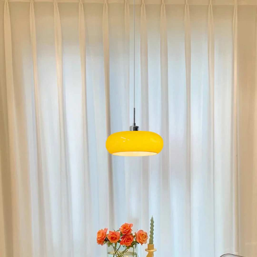 Vibrant orange pendant lamp suspended above a dining table setup