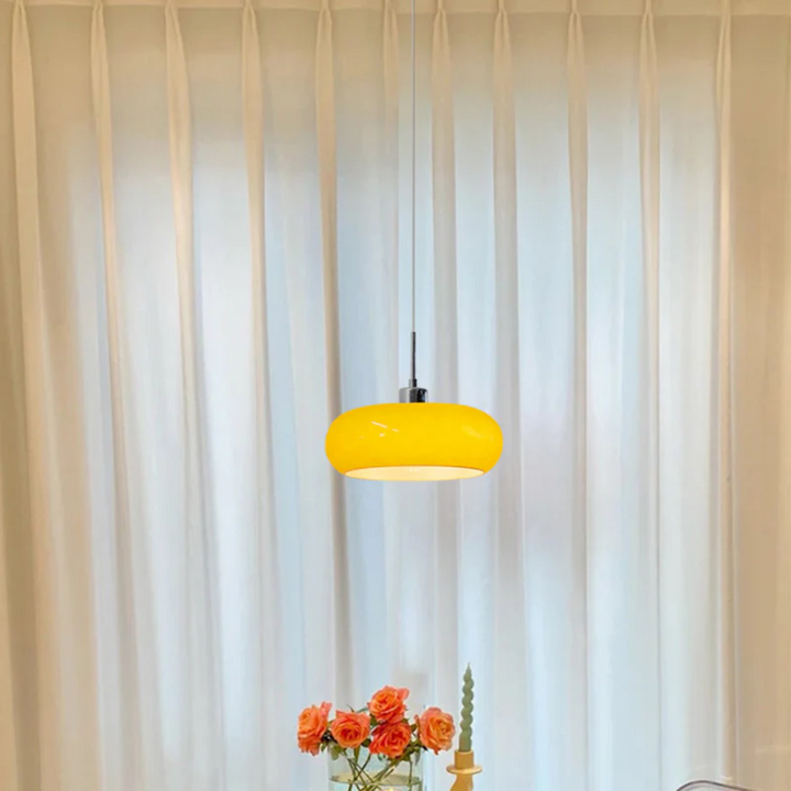 Vibrant orange pendant lamp suspended above a dining table setup