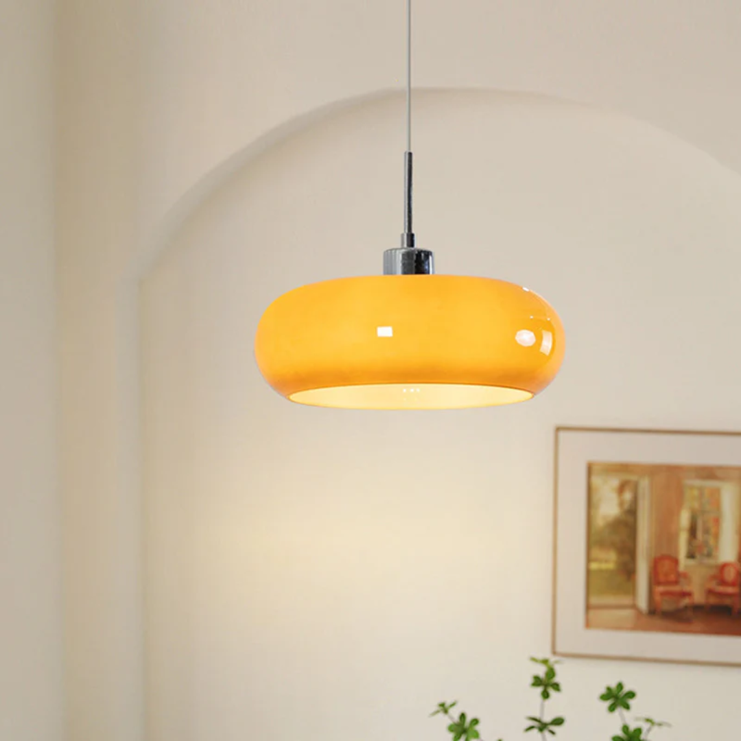 Modern round orange LED pendant light hanging in a brightly lit room