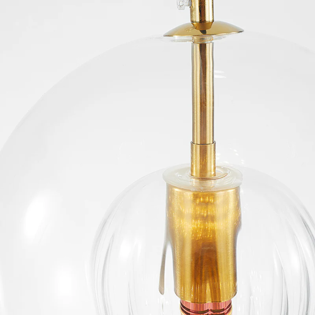 Transparent glass spherical lampshade showcasing the polished gold metal interior socket
