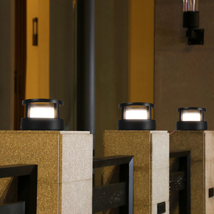 Modern post and pillar light casting warm glow on stone patio floor